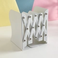 Adjustable white metal bookend with expandable X-frame on a colorful background - Minimalist White