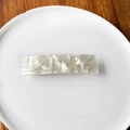 Dettaglio di un fermaglio per capelli in acetato con texture marmo bianco su vassoio - Bianco perla