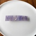 Dettaglio macro di un fermaglio rettangolare con trama in marmo viola su piatto bianco - Viola Chiaro