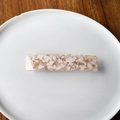 Dettaglio del fermaglio per capelli in acetato rosa e bianco su un piatto di ceramica - Rosa
