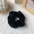 Classic black velvet scrunchie hair tie with soft glossy texture in lifestyle setting - Black