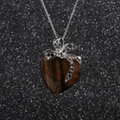 Collier pour femme avec nœud argenté et pendentif cœur en œil de tigre sur fond noir - Marron