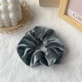 Dark grey velvet scrunchie hair tie on white table with minimalist decor - Gray