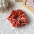 Premium orange-red velvet hair scrunchie shown on a decorative aesthetic background - Orange