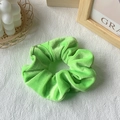 Neon green gold velvet scrunchie with large ruffles shown on a textured fabric background - Green