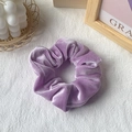 Elegant light purple velvet scrunchie placed on white fabric with decorative props - Blue and Purple