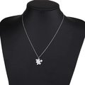 Gros plan d'un collier avec pendentif puzzle argenté sur un mannequin noir - Petit Morceau de Puzzle Couleur Acier