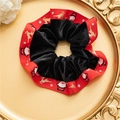 Dettaglio di scrunchie in velluto natalizio con nastro rosso e motivi di renne su piatto - Bordo del pupazzo di neve nero