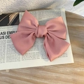 Pink satin large bow hair clip with smooth texture shown on a vintage newspaper background - Duckbill Hair Clips / Dusty Pink