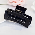 Minimalist black hollow square hair claw clip shown with pink roses and ceramic plate - Glossy Black / Black