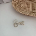 Primer plano de un broche dorado en forma de tijeras con perlas elegantes y pedrería brillante - Estilo Tijeras Diamantes Perla
