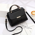 Elegant black leather handbag with golden buckle and adjustable strap on minimalist setup - Black