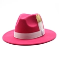 Gros plan détaillé d'un chapeau fedora en laine rose fuchsia avec ruban et plumes élégantes - Rose rouge