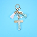 Detail of letter T keychain with light blue stones, gold flakes, and tassels on blue base - Letter T