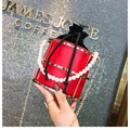 Detailed macro view of luxury red leather bucket bag with gold frame and pearl handle - Red