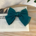 Elegant forest green satin bow hair clip placed on an open book over a wooden background - Duckbill Hair Clips / Dark Green