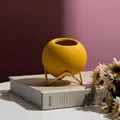 Matte yellow ceramic ball vase with a minimalist golden metal stand for home decor - Earthy Yellow