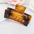 Macro view of a square hollow hair claw clip in amber leopard print with golden spring - Amber/Tortoiseshell / Coffee