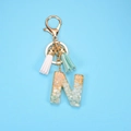 Letter N keychain with gold foil, mint stones, and colorful tassels on blue background - Letter N