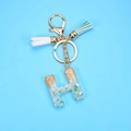 Detail of resin letter H keychain with green stones, gold flakes and colorful tassels - Letter H