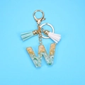 Detail of resin letter W keychain with gold foil flakes, green stones, and leather tassels - Letter W