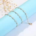Golden eyewear chain with white pearls and lobster clasp on a light blue display stand - Bezel Faux Pearl