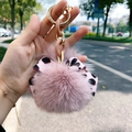 Pink fur pompom keychain with leopard bow and pink chain detail shown in hand - Dusky Pink