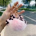 Detailansicht eines rosa Fellbommel-Schlüsselanhängers mit Leoparden-Schleife und Kette - Hellrosa