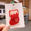 Close-up of a handmade red knitted Christmas stocking hair clip with snowflake embroidery - Christmas Sock