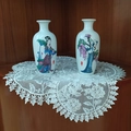 Close-up of a white lace embroidered coaster under elegant decorative ceramic vases - Narcissus