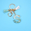 Detail of resin letter S keychain with green stones, gold flakes and tassels - S