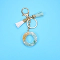 Detail view of resin letter O keychain with gold foil, green stones and dual tassels - Letter O
