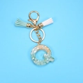 Detailed macro view of letter Q resin keychain with green stones and gold foil flakes - Letter Q