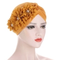 Détail du turban jaune orné de trois fleurs en tissu avec perles et strass brillants - Curcuma