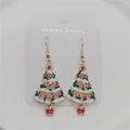 Close-up of Christmas tree drop earrings with green enamel and golden hooks - Christmas Tree