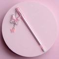 Penna gel rosa e bianca con ciondolo a farfalla glitterata su un supporto pastello - Rosa