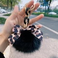 Detail of soft black fur pompom with leopard print bow and gold chain keychain - Black