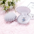 Detailed view of an open shell jewelry box with a blue gemstone necklace on plush fabric - Grey Shell