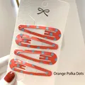 Set of 4 orange metal hair clips with light blue polka dots on a display card - Orange with Blue Polka Dots