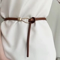Gros plan d'une ceinture en cuir marron avec boucle fer à cheval dorée et détail de nœud - Marron