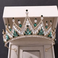 Detailed close-up of golden Baroque crown with white and green crystals in a jewelry box - Gold with Green Rhinestones