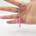 Close-up of a colorful resin mushroom keychain with white dots and silver metal ring - Rose Red