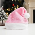 Pink plush Christmas hat with white fur trim and pompom against a festive holiday background - Pink
