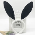 Detail of plush black and white bunny ear headband on white background with dried flowers - White and Black Rabbit