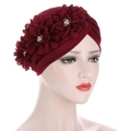 Détail d'un turban rouge avec trois fleurs appliquées ornées de perles et de strass - Bordeaux