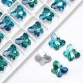 Macro detail of 14mm butterfly crystal charms with teal facets and silver backings for DIY - Green