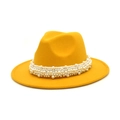 Detailed close-up of a mustard yellow fedora hat with an elegant faux pearl band decoration - Yellow