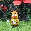 Wind-up reindeer Christmas toy in orange plastic with yellow scarf on grass - Head-shaking Reindeer