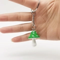 Dettaglio portachiavi a fungo in resina verde e bianco con anello metallico su sfondo chiaro - Verde