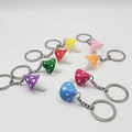 Top view of eight colorful resin mushroom keychains with white dots on white background - Multicolor